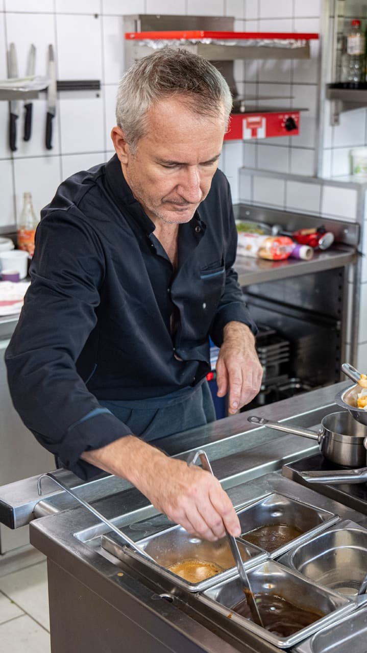 Photographie d'un cuisinier préparant un plat au Café du Raisin.