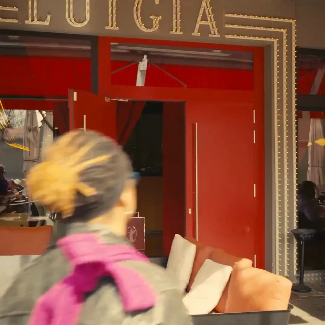 Façade du restaurant Luigia, portes rouges et enseigne à ampoules, passante floue au premier plan